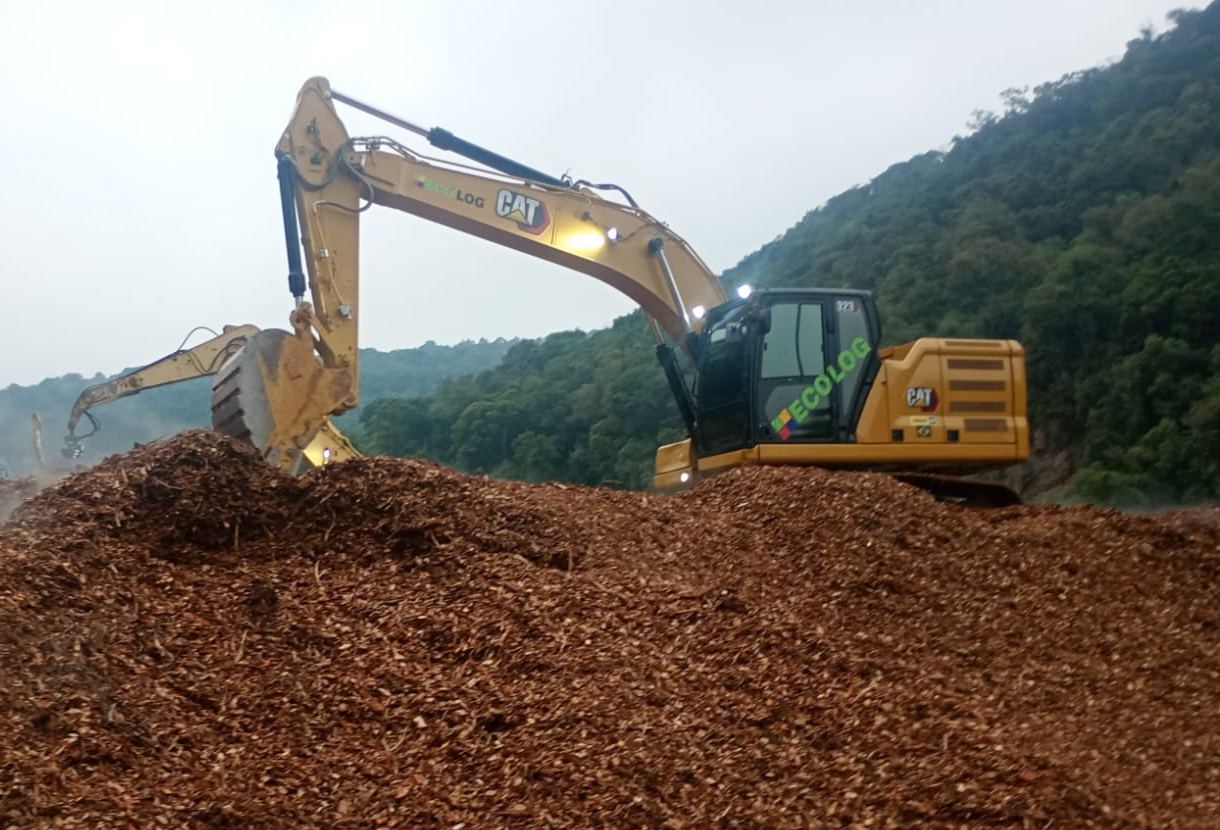 Escavadeira sobre monte de cavaco para reaproveitamento